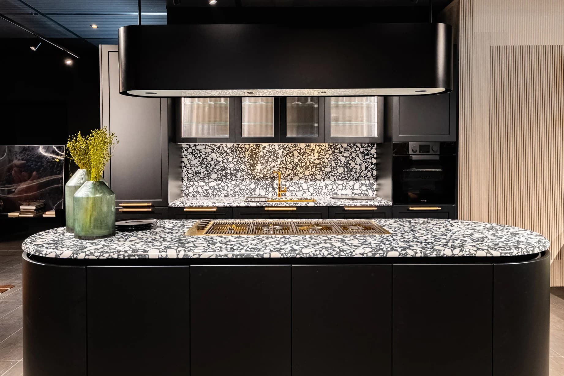 Ancona kitchen with matt black cabinetry, patterned terrazzo worktops, ribbed glass and brass handles