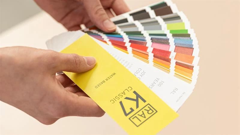 Hands holding a fan of labelled colour swatches