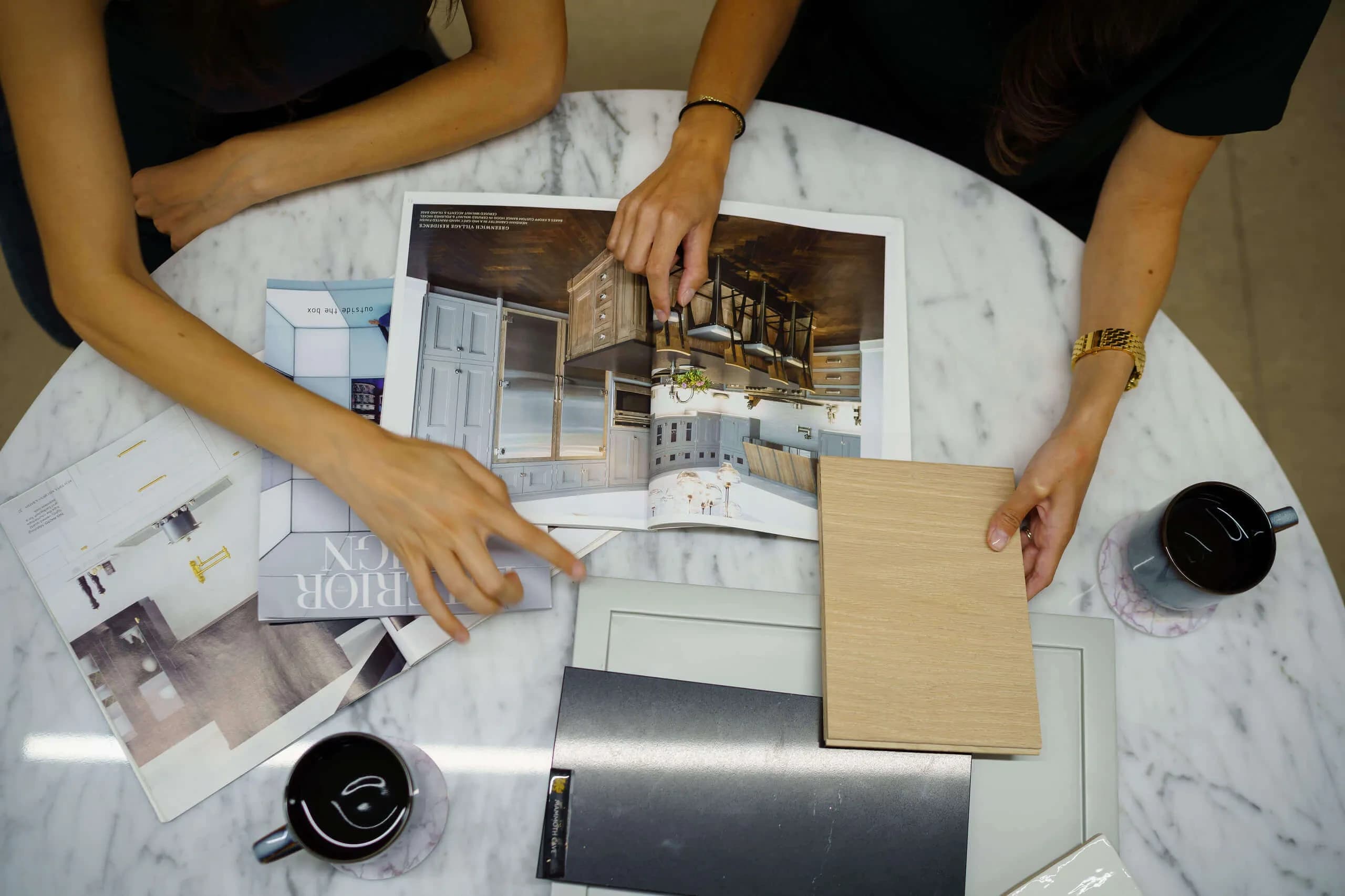 People comparing sample boards over a kitchen plan