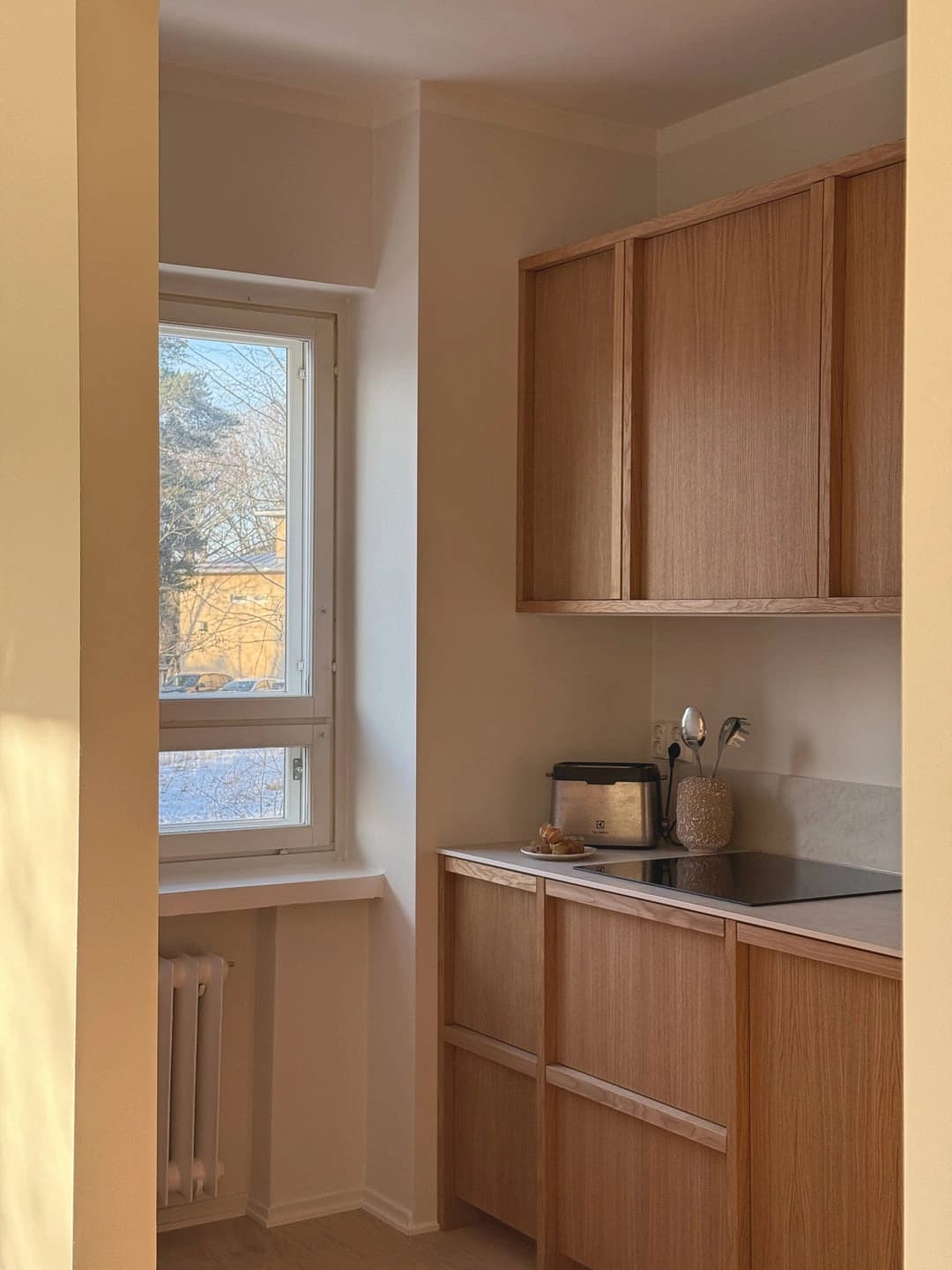 Oak-toned cabinetry beneath a window in a kitchen