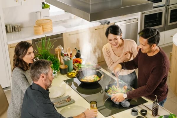 Four people preparing food around a kitchen island