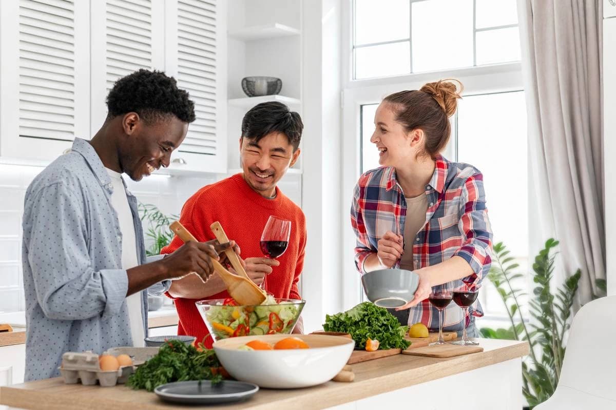 Three people preparing vegetables together in a kitchen