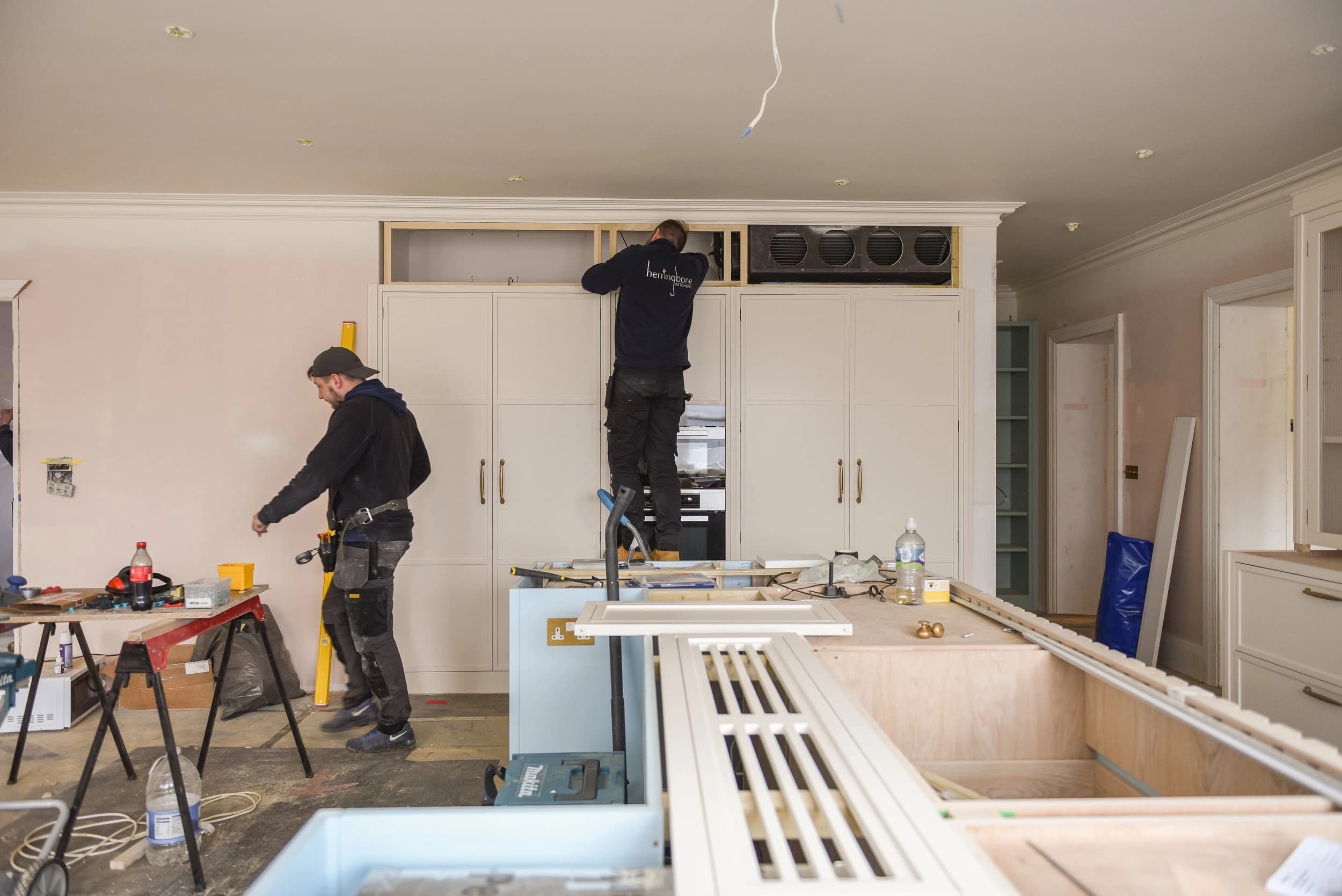 Workers fitting cabinetry in an unfinished kitchen