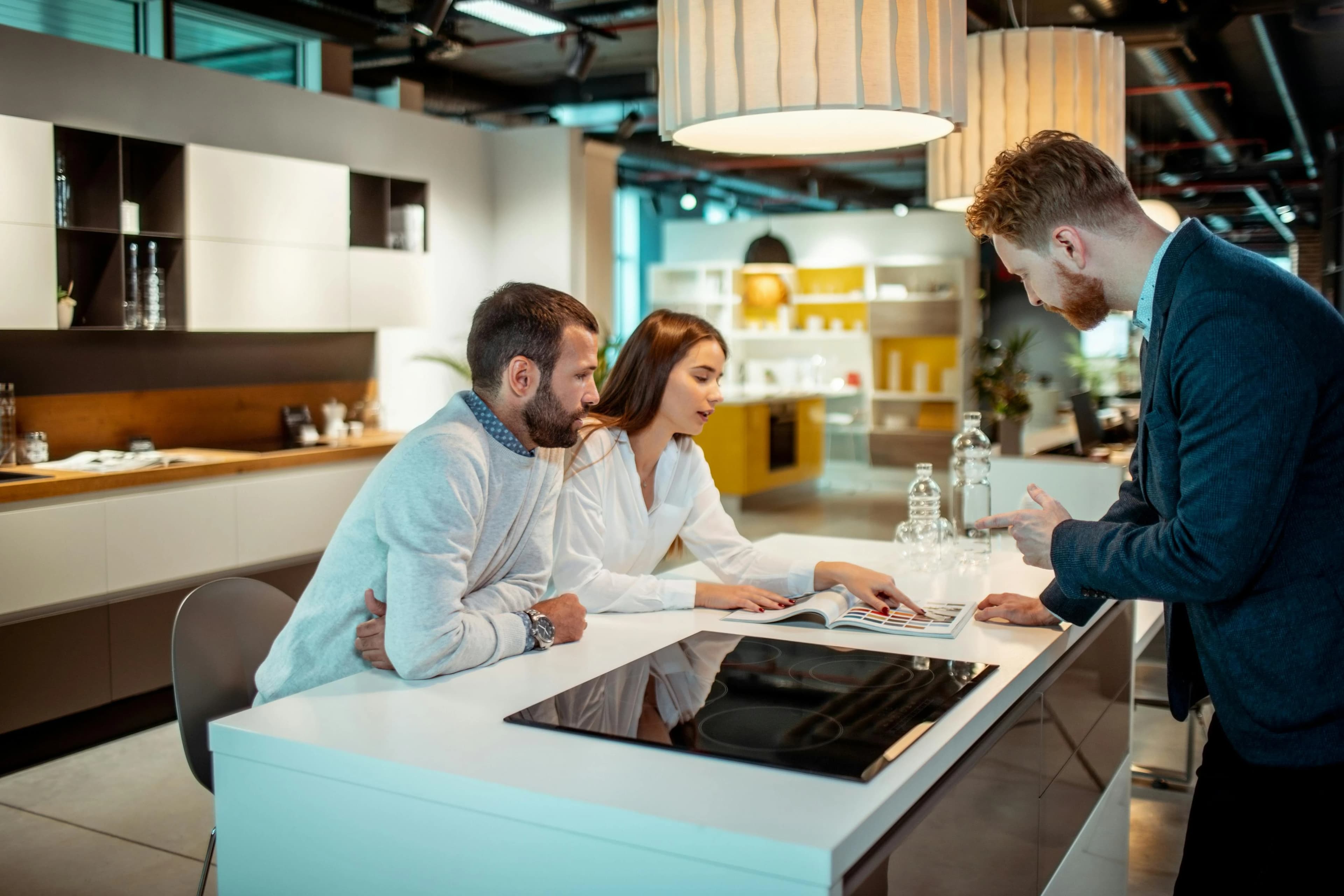 Three people discussing a plan at a kitchen showroom counter