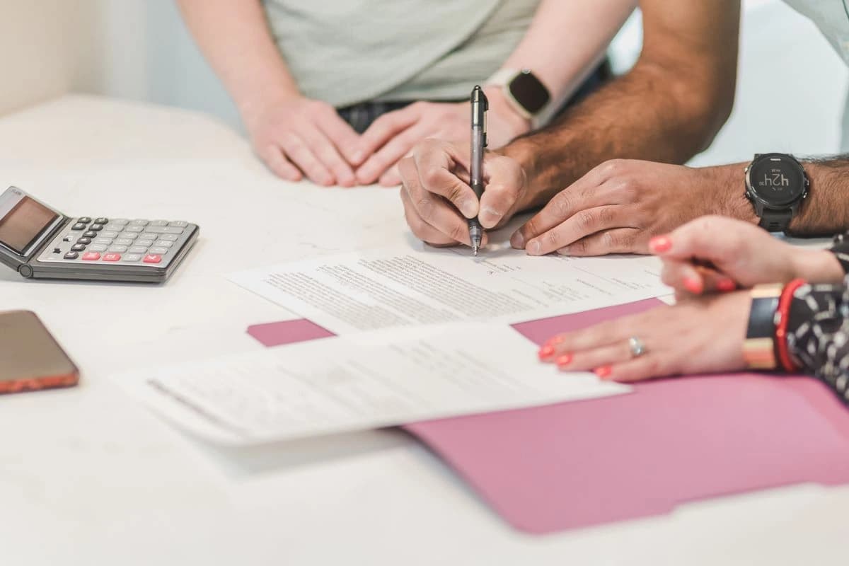 Hands reviewing paperwork beside a calculator