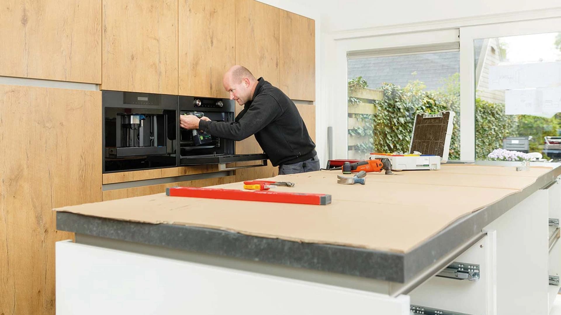 Installer working on a built-in oven in timber cabinetry
