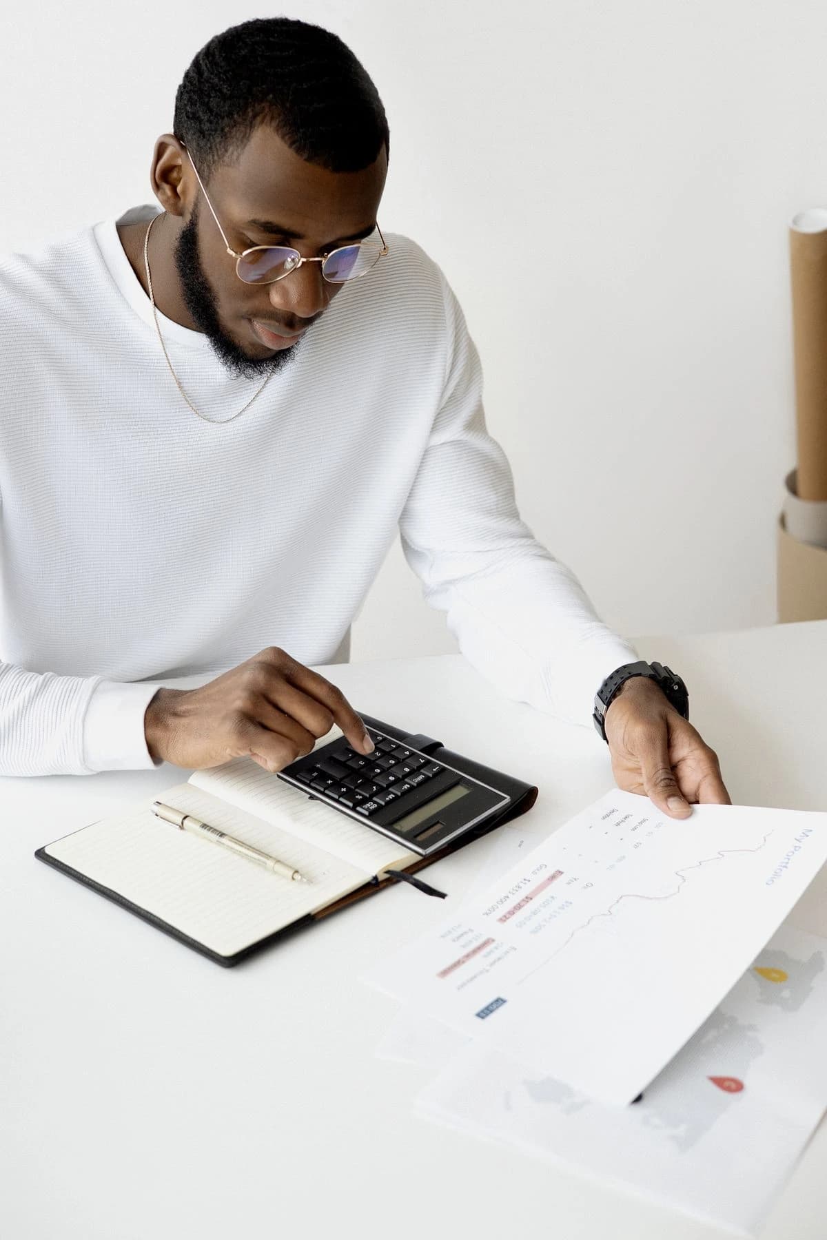 Person writing beside a laptop and financial paperwork