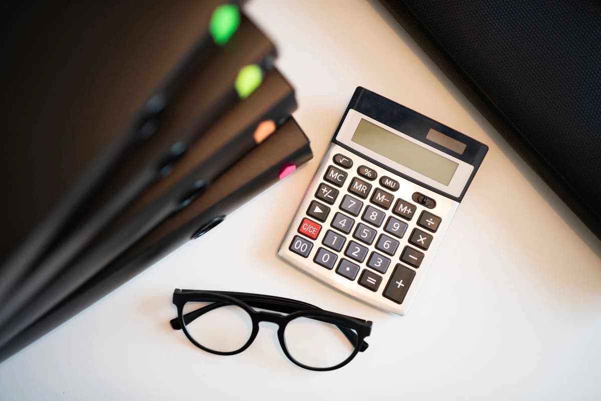 Calculator, glasses, pencil and notebook on a desk