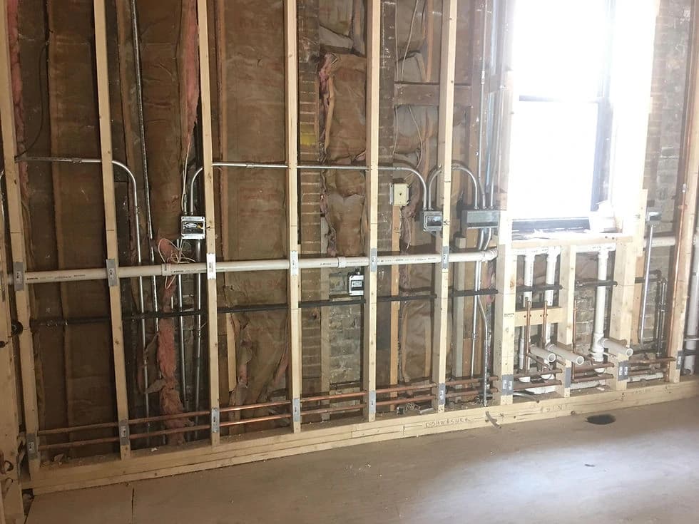 Open wall framing with visible pipework and electrical services