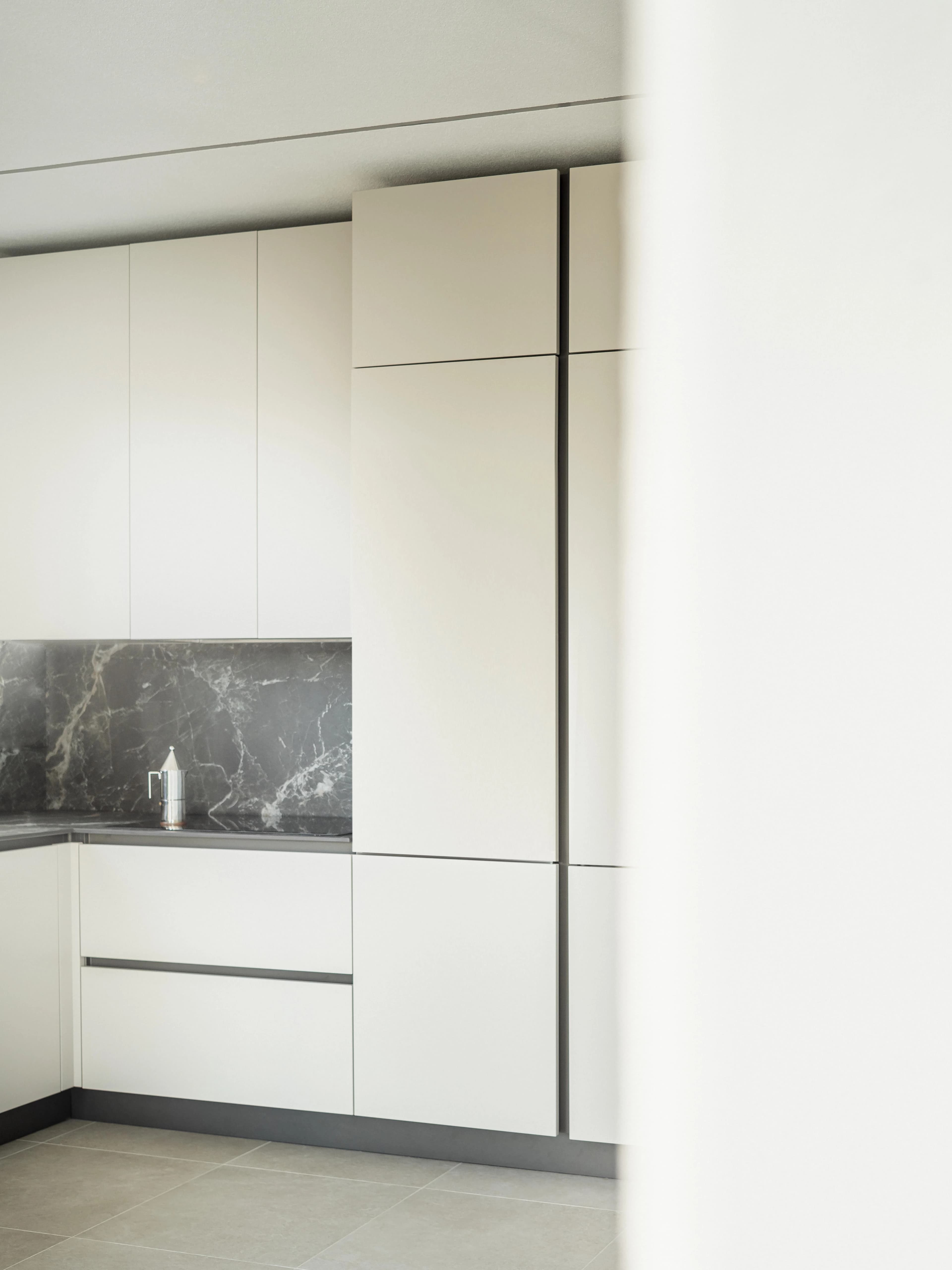 Pale full-height kitchen cabinetry beside a stone splashback