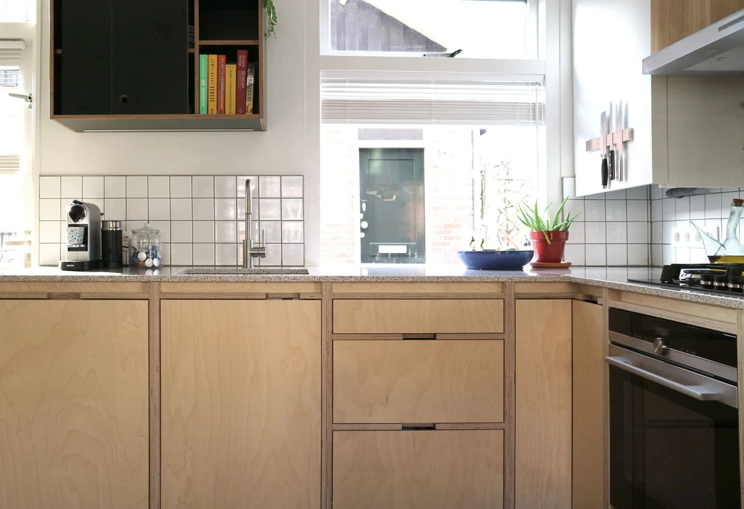Timber kitchen cabinets with visible ply edges and a sink beneath a window