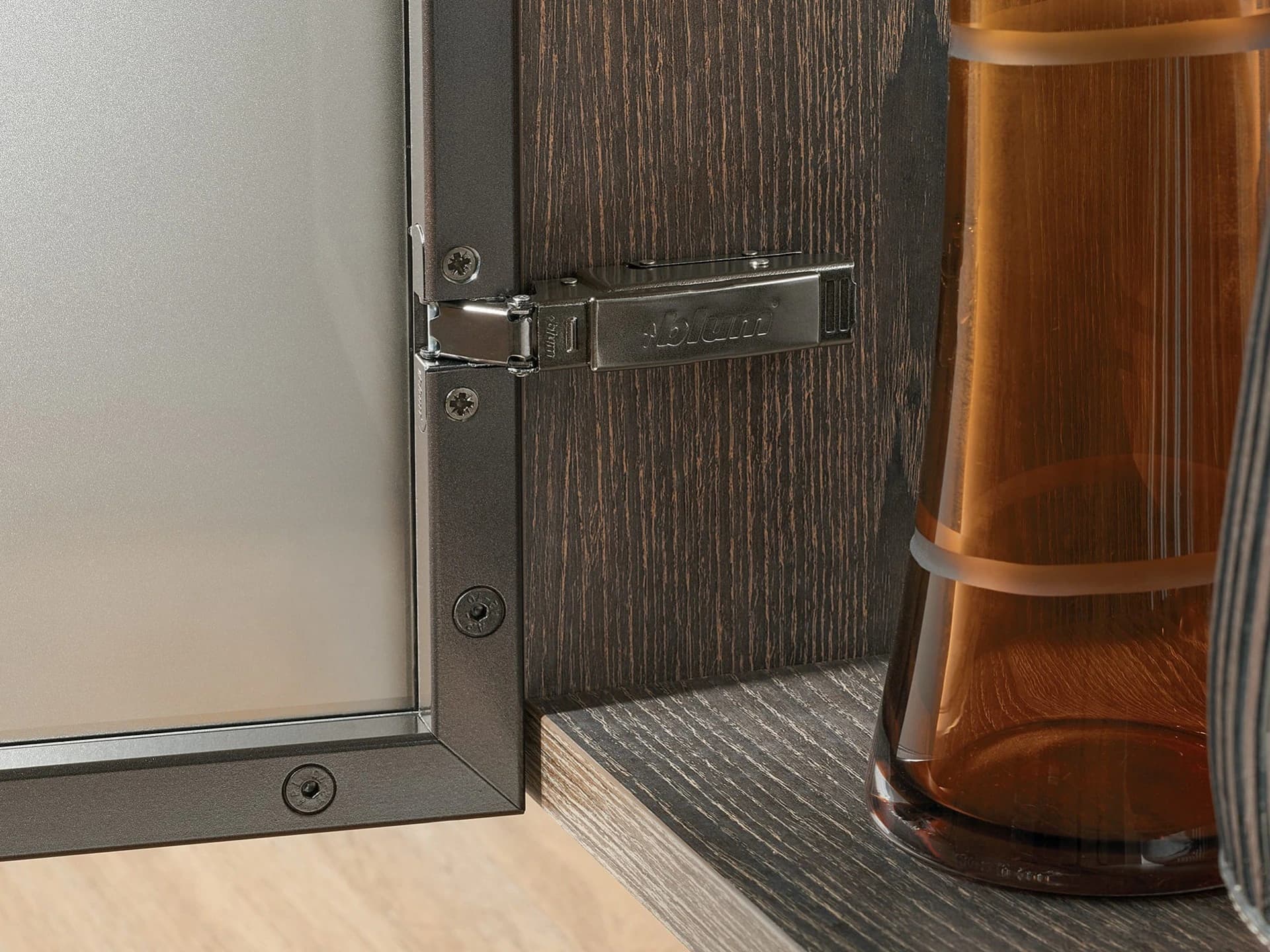 Dark hinge fixed to an open timber cabinet door