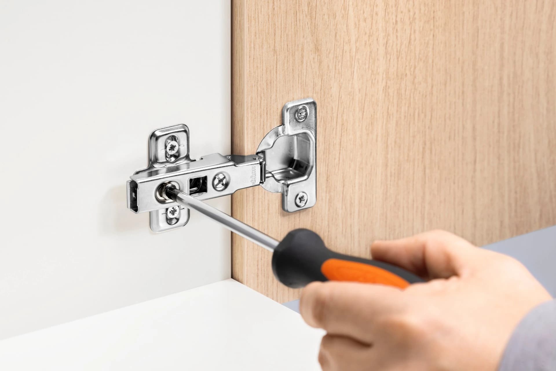 Screwdriver adjusting a concealed cabinet hinge