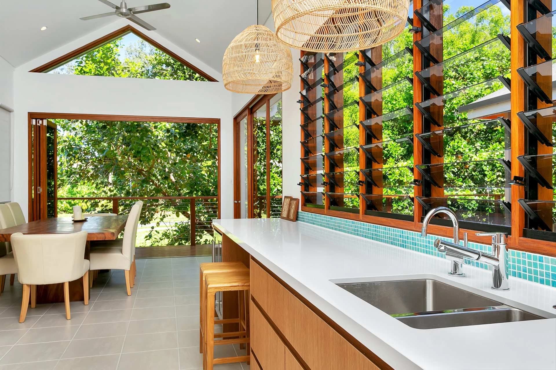 Light kitchen with open timber shutters and greenery outside