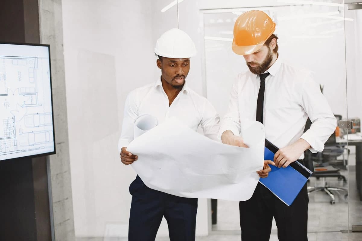 Two people wearing hard hats reviewing a drawing