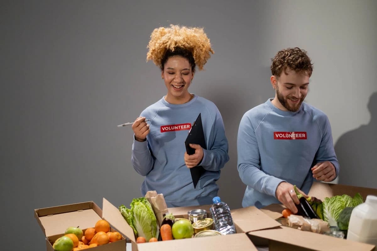 Two people sorting vegetables beside cardboard boxes