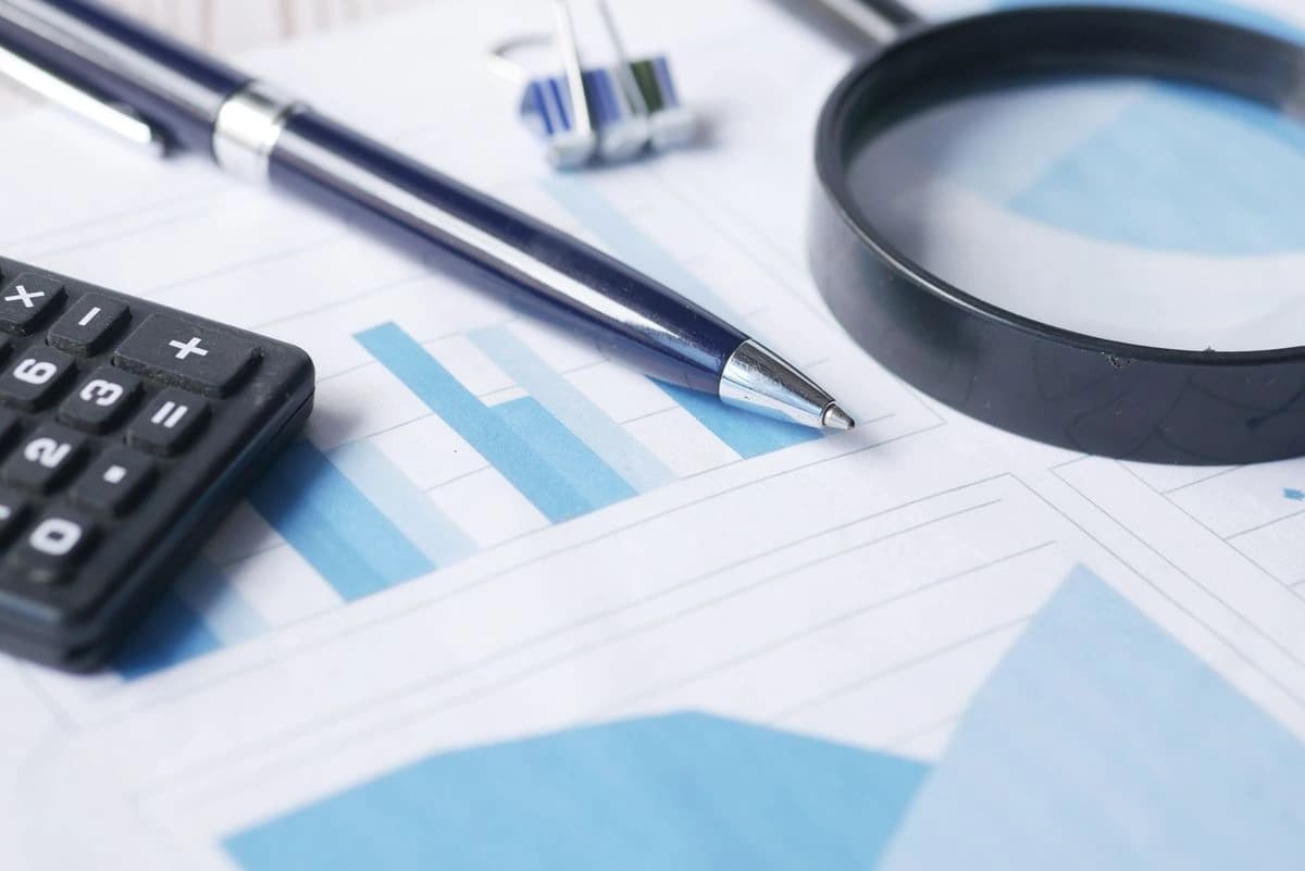 Calculator, charts, pen and magnifying glass on a desk