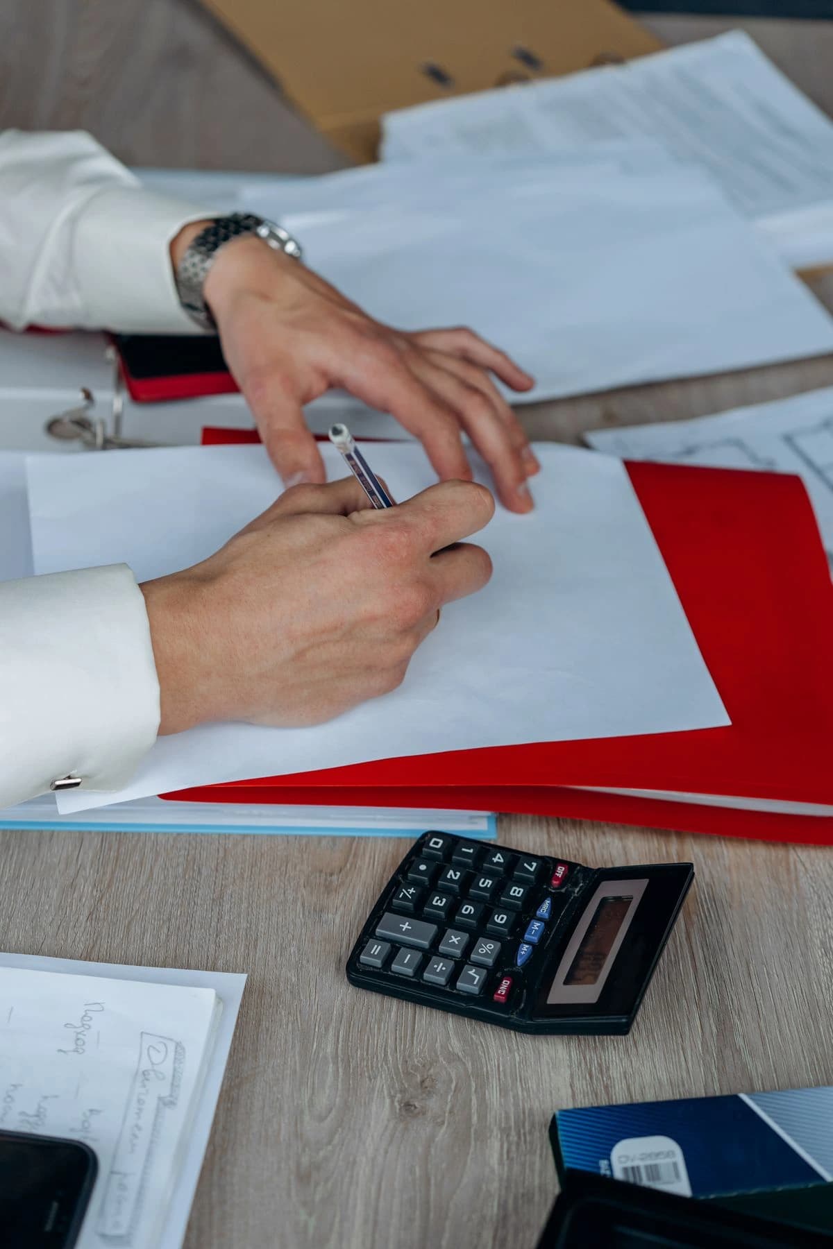 Hands reviewing a document beside a calculator