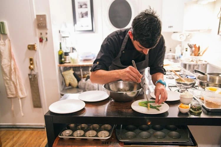 Cook arranging food on plates beside a stove