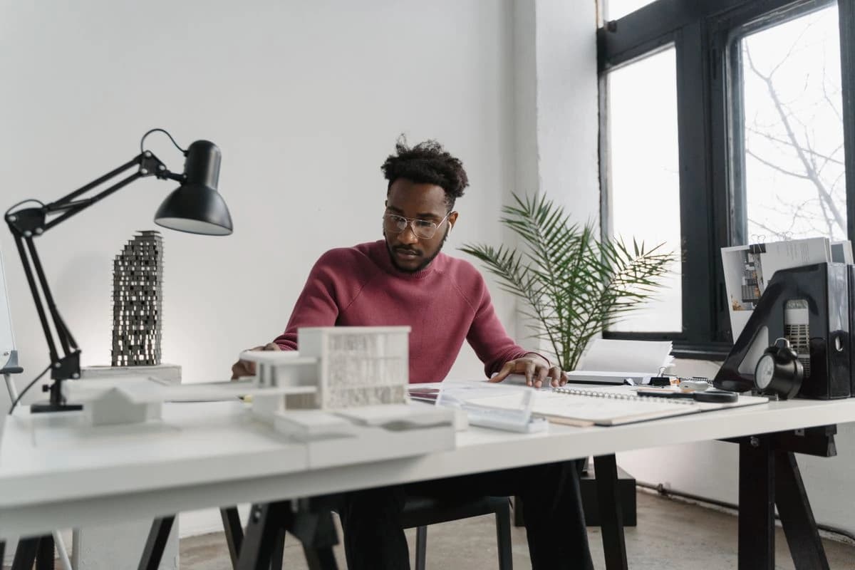 Person drawing at a desk beside a laptop