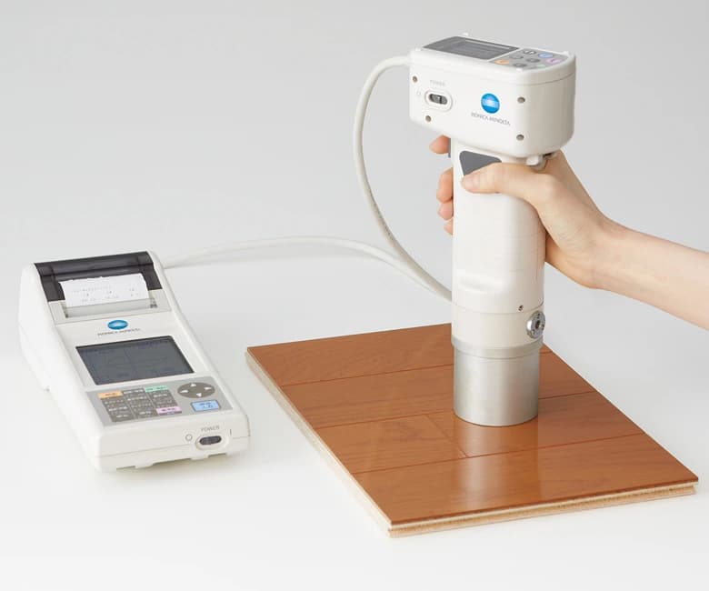 Handheld colour-measuring device above a timber sample
