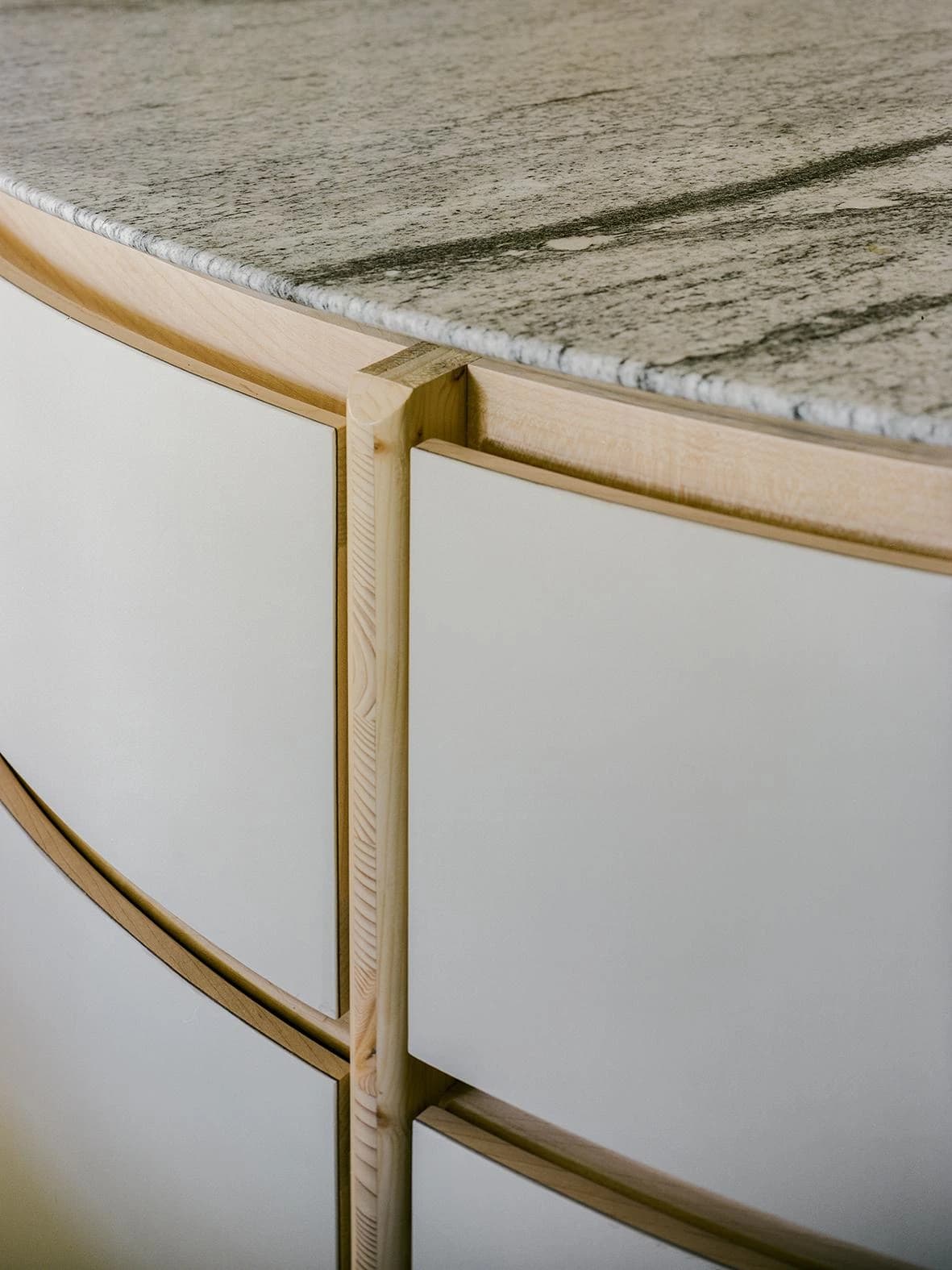 Curved kitchen cabinet fronts beneath a stone worktop