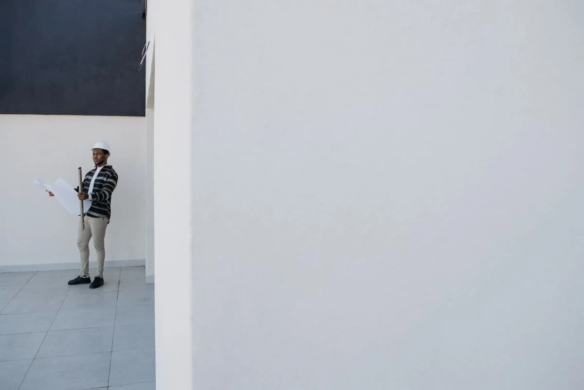 Person holding a drawing in an unfinished room