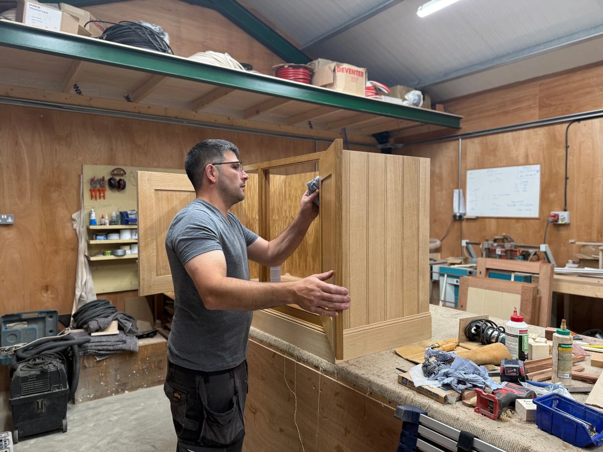 Person fitting a tall timber cabinet in a workshop