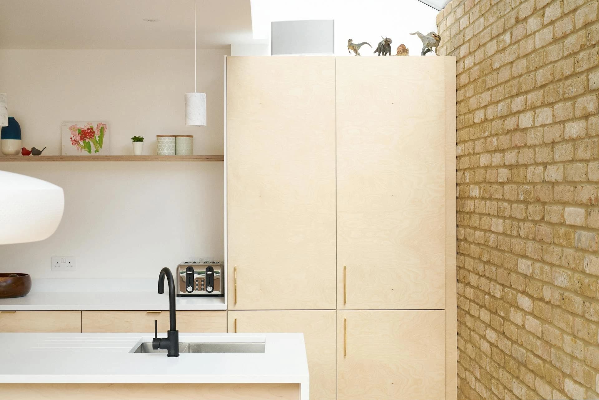 Timber kitchen cabinetry with an exposed brick wall and a small dining area
